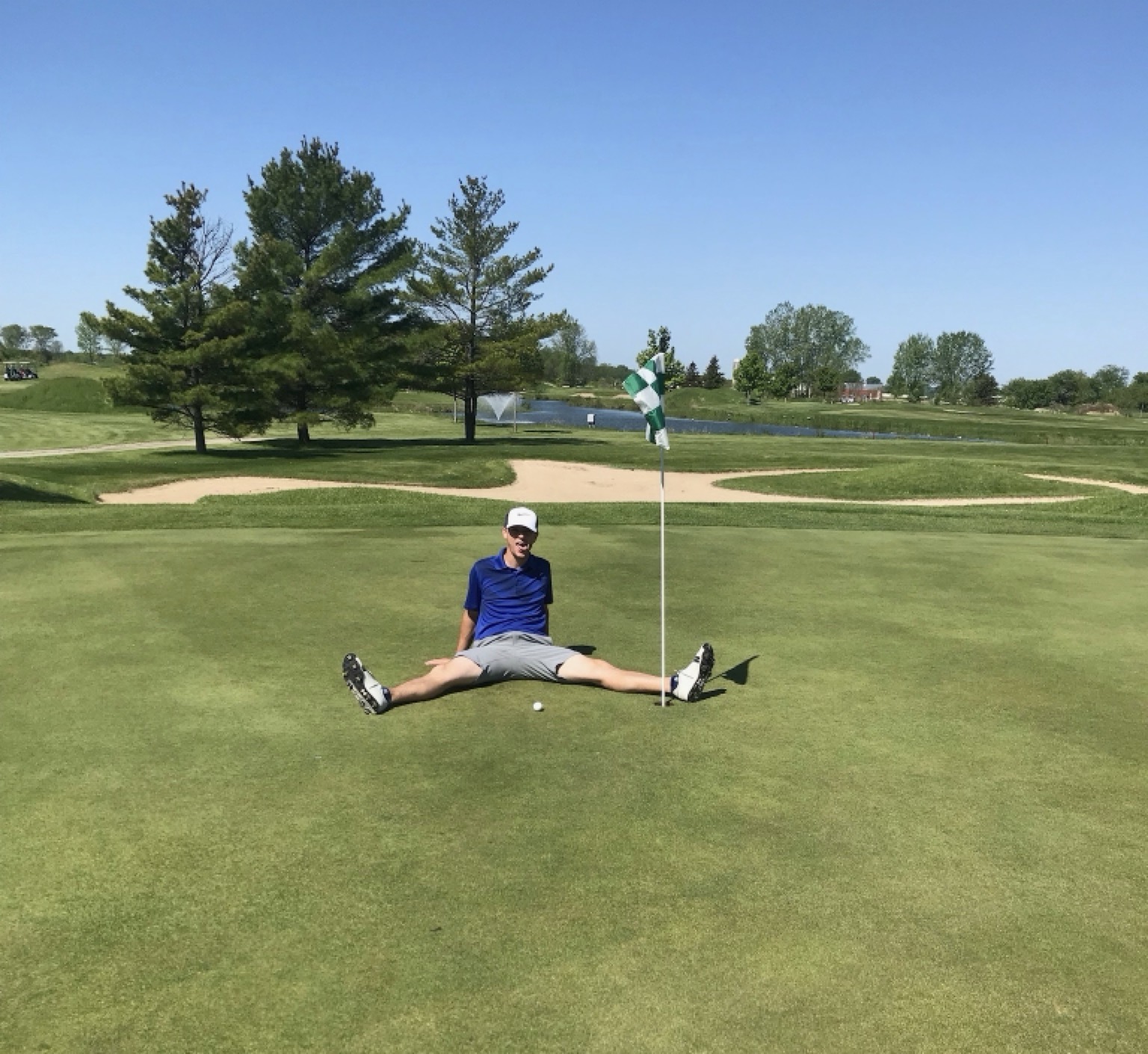 Jake Willis sitting on the green after a close approach shot