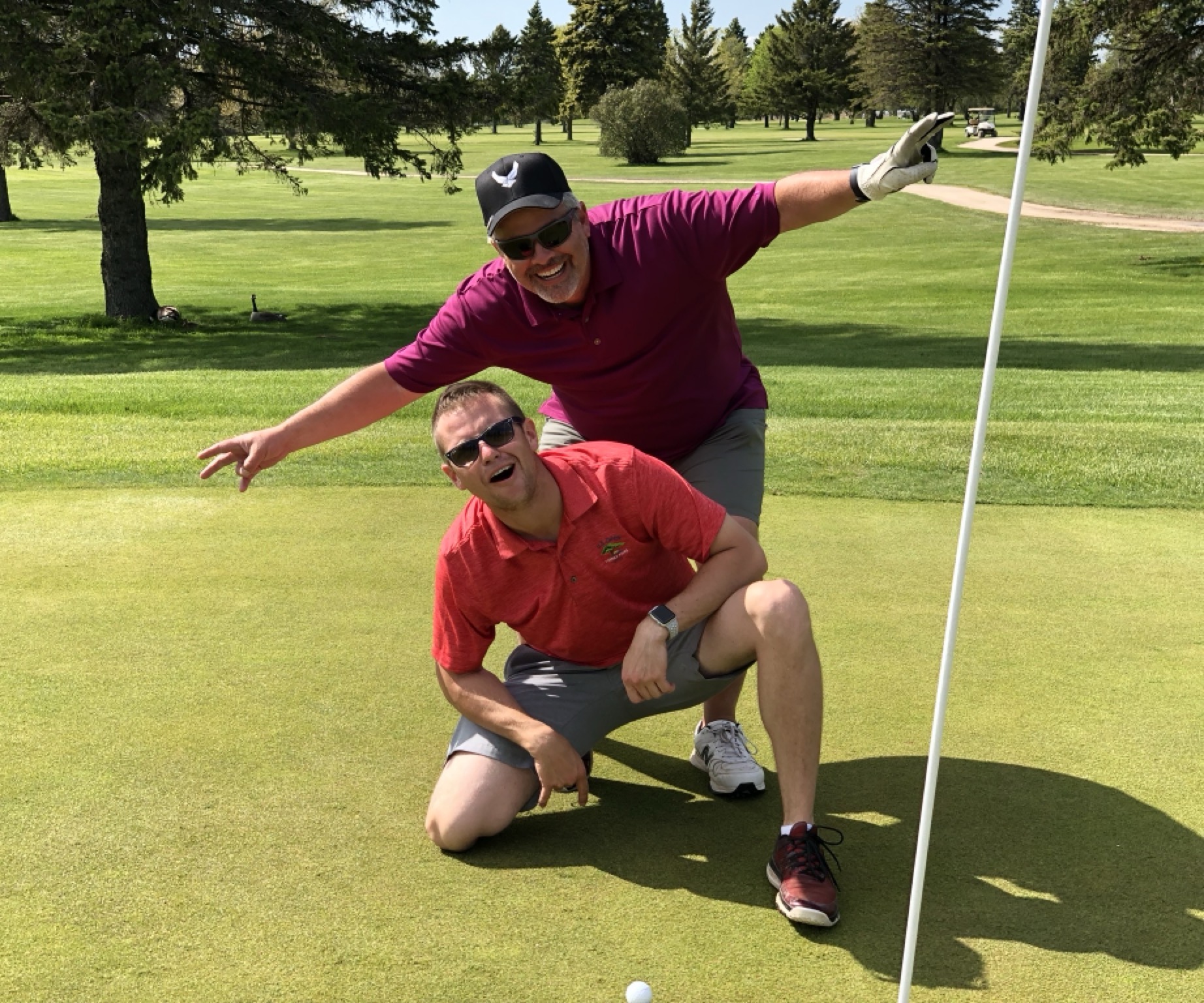 Jake kneeling next to a shot on a par 3 with Dean behind him